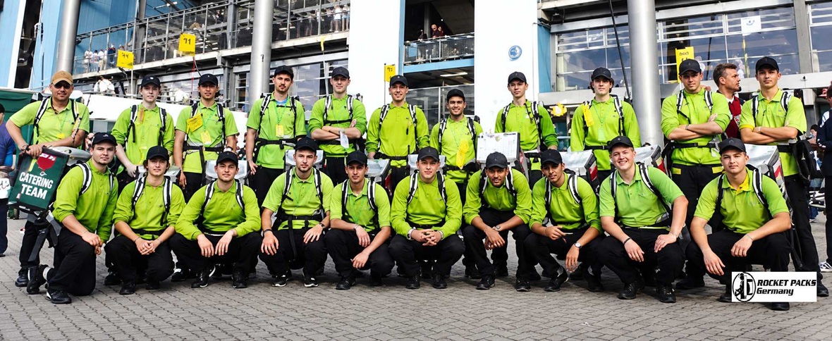 Stadium catering team equipped with mobile vending backpacks for beverage distribution during sporting events.