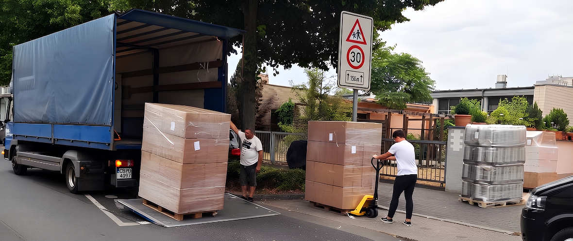 Palletized commercial goods being loaded onto a truck for international shipment